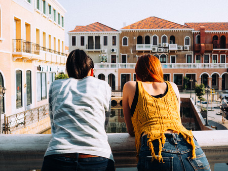 Two Asian tourist girls walking around the city for sightseeing with one of them leading the way.の写真素材