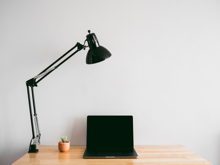Laptop and some stationary items on wooden work desk with empty gray wall as background. Concept of workspace and minimal freelance office.の写真素材