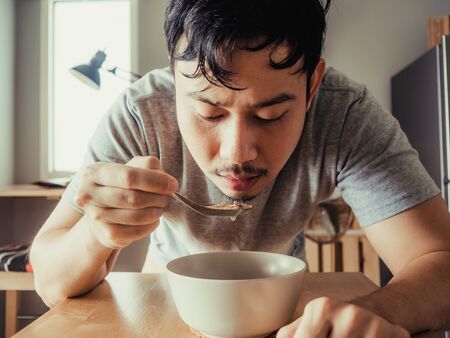 Asian man is having a boring bolw of cereal as breakfast.の写真素材