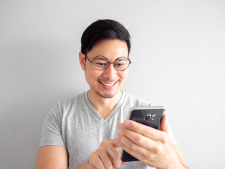 Happy Asian man is using smartphone. Concept of using social media on mobile phone.の写真素材