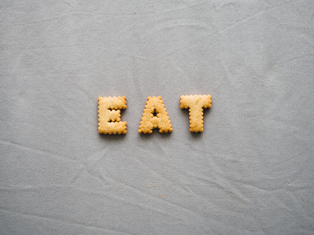 Bicuits arrange into word on grey background. Concept of word EAT.の写真素材