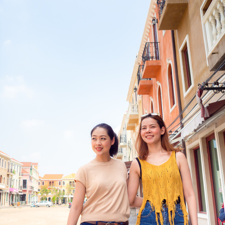Two Asian women best friends walking on beautiful European street for a travel trip of sightseeingの写真素材