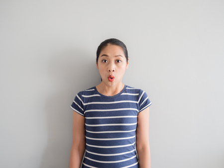 Shocked and amazing face of Asian woman on grey background.の写真素材