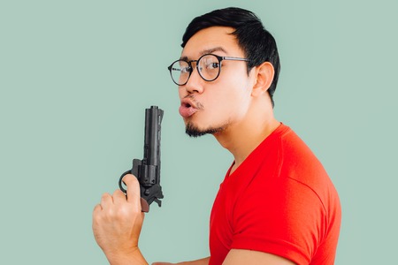 Confident Asian man is blowing the gun smoke.の写真素材