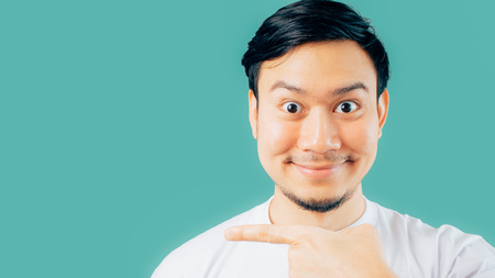 Happy Asian man with hand point on empty space on isolated background.の写真素材