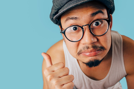 Funny Asian man pointing with his thumb with disagree face.の写真素材