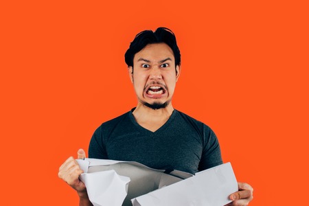 Angry Asian man is tearing package box expression.の写真素材