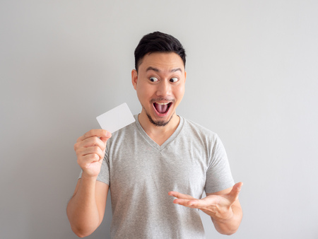 Happy Asian man is showing a white credit card.の写真素材