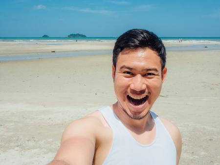 Happy Asian man selfie himself on the sunny summer beach.の写真素材