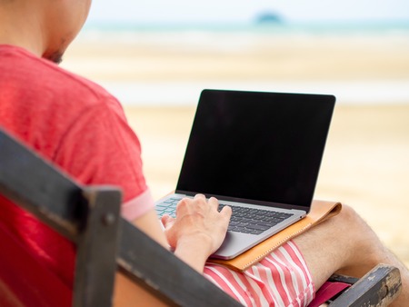 Man relax on camp bed and working online while on vacation at the beach in Thailand.の写真素材