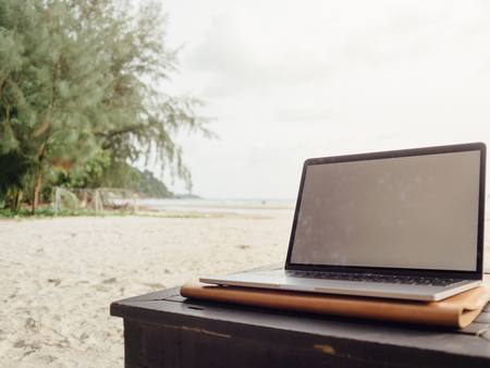 Working with laptop while on vacation at tropical beach.の写真素材