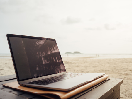 Laptop computer on the table in the beach. Concept of work and summer vacation.の写真素材