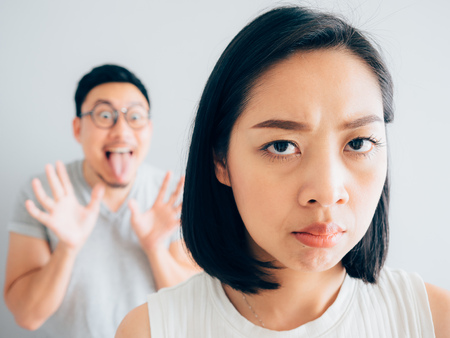 Annoyed Asian wife and funny tricky husband.の写真素材