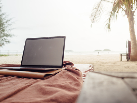 Working with laptop while on vacation at tropical beach.