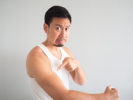 Painful face Asian man in white tank top get sunburn on the arm.