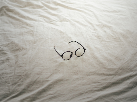 Eyeglasses on white bed in one fine good morning.の写真素材