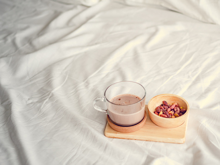 Small snacks set of salted beans and hot chocolate served on the bed in the morning.