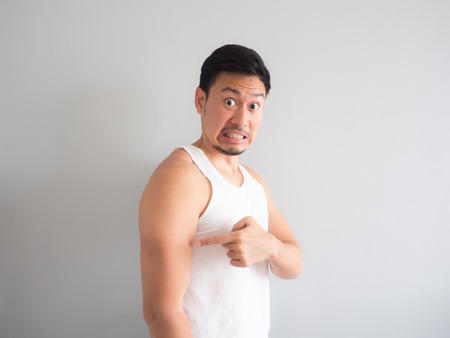Painful face Asian man in white tank top get sunburn on the arm.