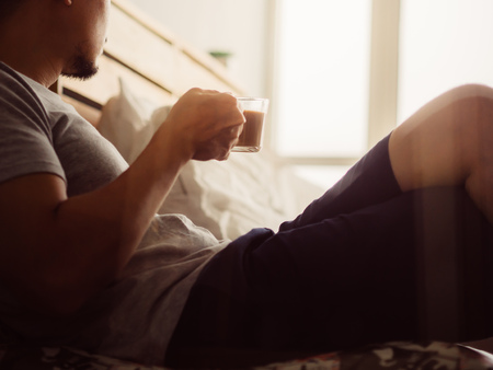 Asian man drink hot coffee and relax in his room. Focused on the good atmosphere.