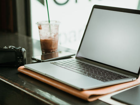 Empty screen laptop with camera and ice coffee in the cafe. Concept of freelance work.