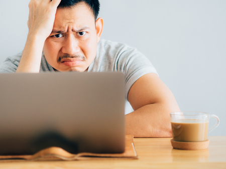 Serious and boring face of asian man work on laptop.