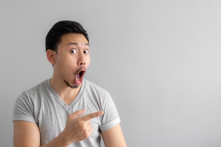 Wow and shocked face of Asian man point to present an empty space of content. Advertising model concept.の写真素材