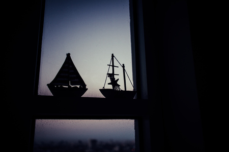 Sailboat model on the edge of the window with velvet sky.
