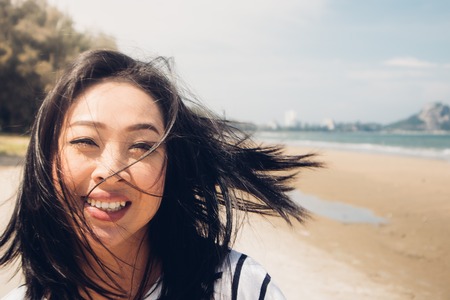 Happy and playful asian woman walking on the beach.