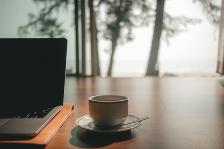 Laptop and coffee cup on wooden floor with warm morning light in concept of work and relax.の写真素材