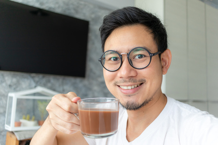 Happy asian man with eyeglasses and white shirt selfy himself drink hot coffee.