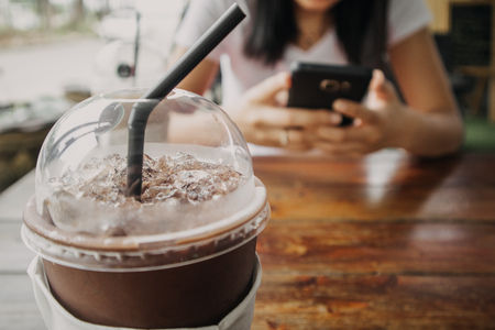 Iced coffee and cocoa drink in plastic cup on wooden table.の写真素材