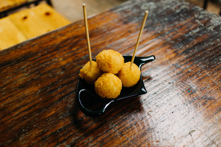 Fried cheese balls served on wooden table in the cafe with sticks.の写真素材