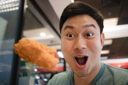 Close up of funny face Asian man eat fried chicken.の写真素材