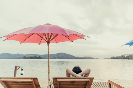 Asian woman rest on the beach in the resort admire the beauty of the nature lake.の写真素材