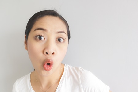Surprised and wow face expression of Asian woman in white t-shirt. Concept of happy and impressive.の写真素材