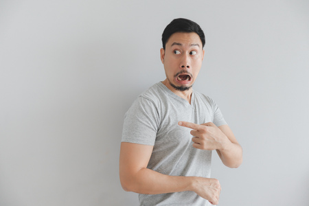 Shocked face of Asian man in grey t-shirt with hand point on empty space.の写真素材