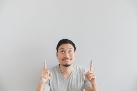 Happy face of Asian man in grey t-shirt with hand point on empty space.の写真素材