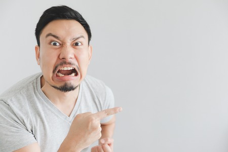 Angry face of Asian man in grey t-shirt with hand point on empty space.の写真素材