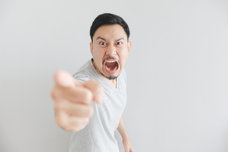 Angry face of Asian man in grey t-shirt with hand point on empty space.の写真素材