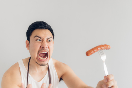 Asian man is angry on the sausage as it is not what he expected for his diet or not delicious.の写真素材