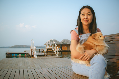 Happy Asian woman enjoy relax with her pomeranian dog.の写真素材
