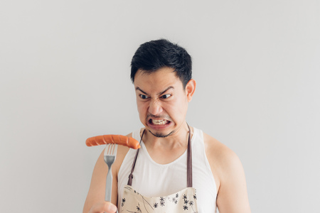 Asian man is angry on the sausage as it is not what he expected for his diet or not delicious.の写真素材