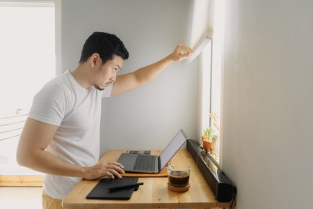 Asian freelancer man is working on his laptop in his apartment. Concept of freelance creative works.