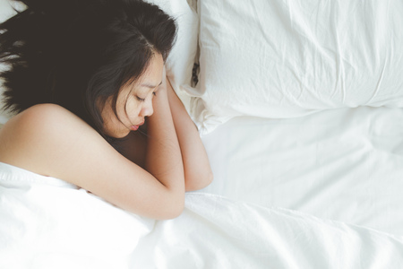 Asian woman has a deep sleep on white bed. Concept of tried and rest.の写真素材