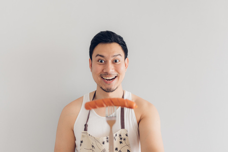 Happy face of Asian man proud to eat and cook sausage. Concept of hate and diet.の写真素材