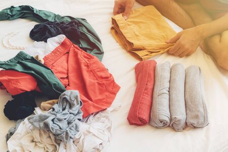 Man is folding and arranging the clothes on the bed after wash them.の写真素材