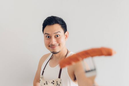 Happy face of Asian man proud to eat and cook sausage. Concept of hate and diet.