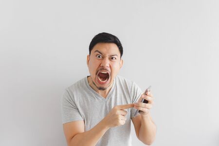 Angry Asian man in grey t-shirt get mad on the smartphone.の写真素材