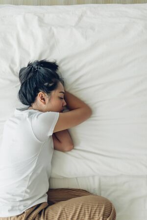 Top view of Asian woman sleeping on her bed with white copy space.の写真素材
