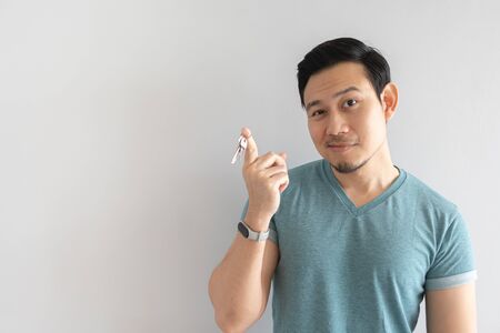 Asian man with funny face showing the key. Concept of outdated useless key.